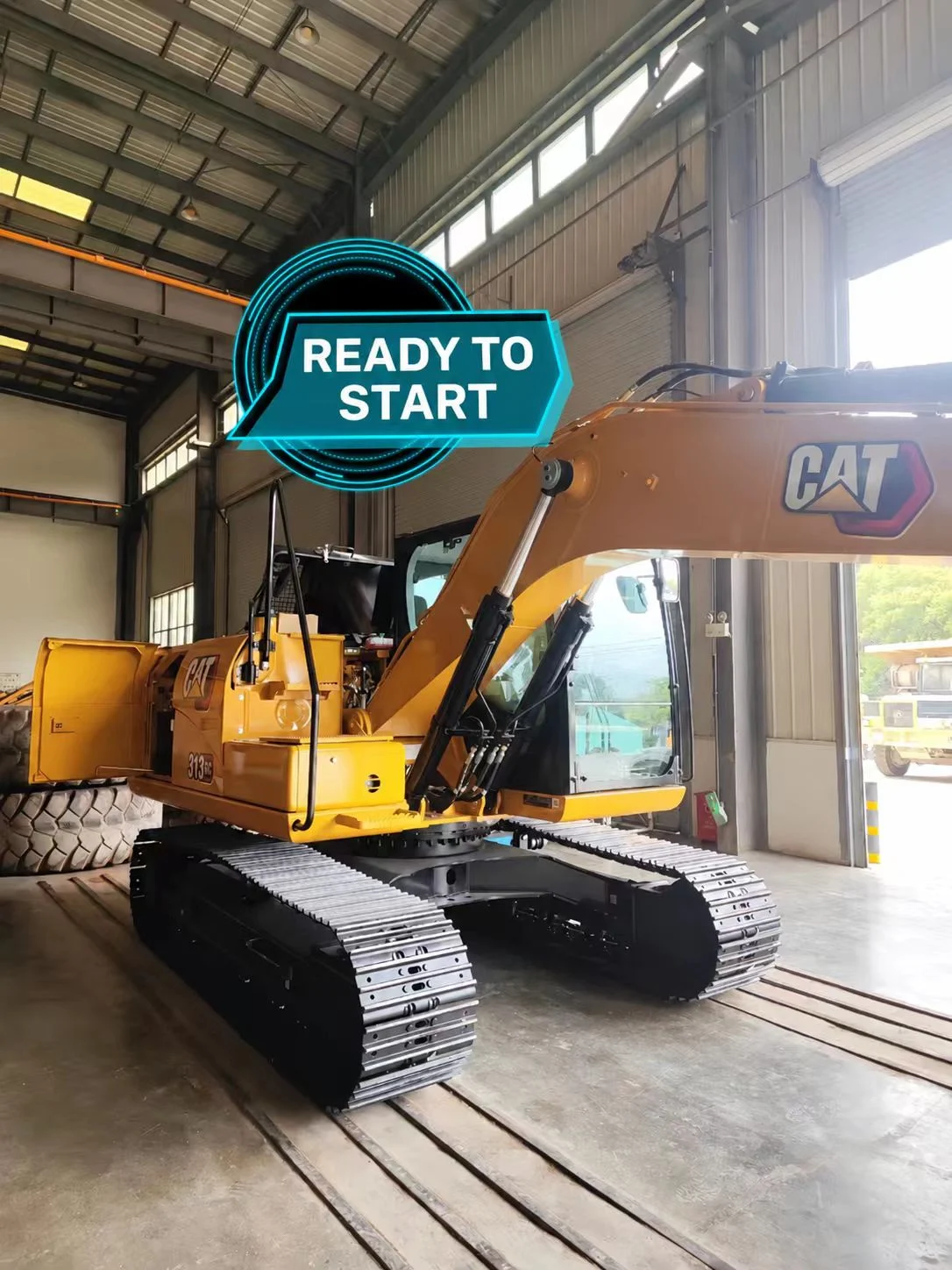 CAT 313 GC inside a workshop with its front undercarriage visible.
