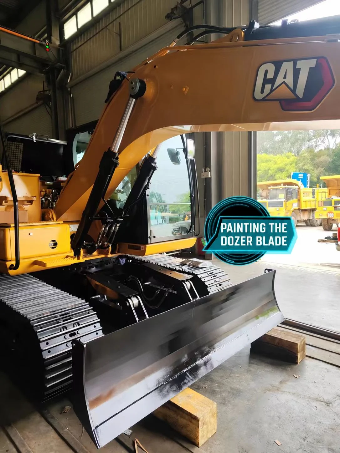 Front-mounted excavator blade during finishing, with dark coating on its upper surface.