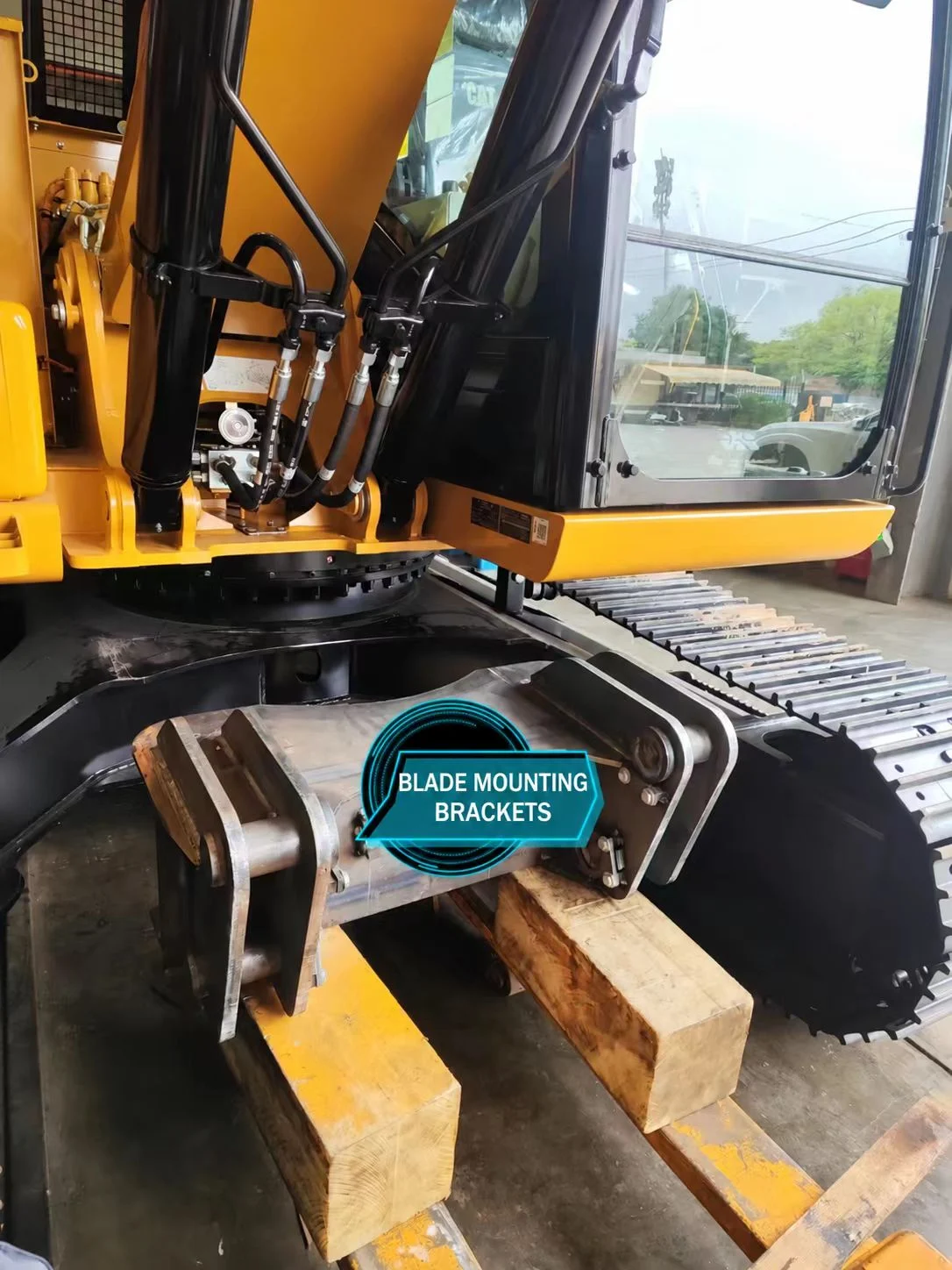 Steel blade mounting brackets being positioned between the excavator tracks.
