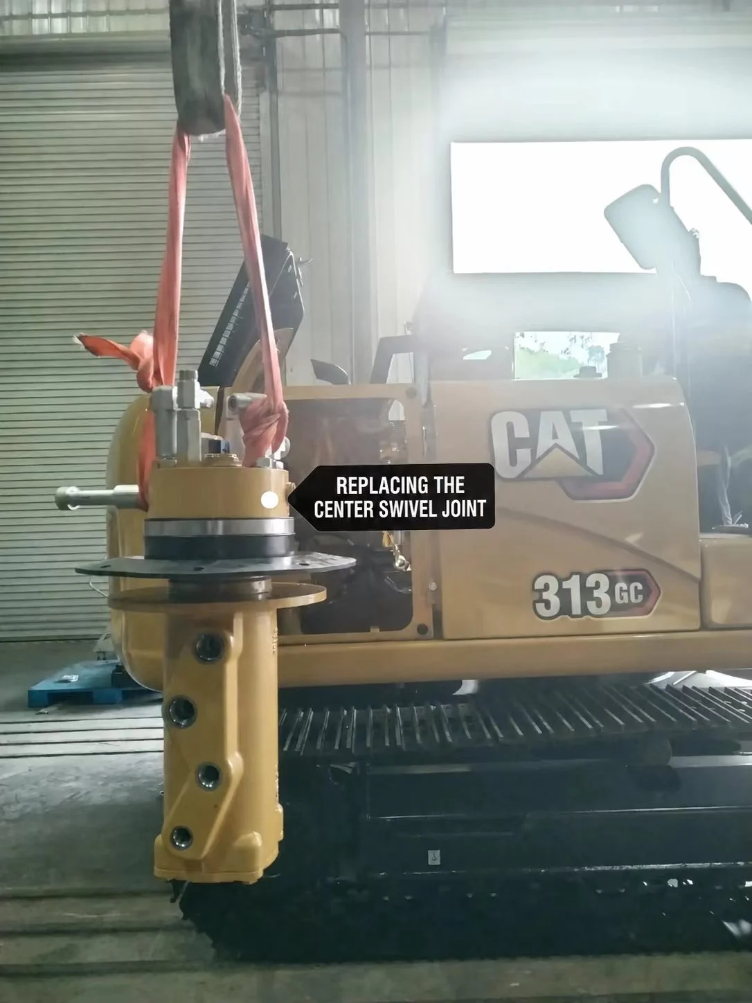 Center swivel joint suspended beside a machine carrying CAT 313 GC markings.